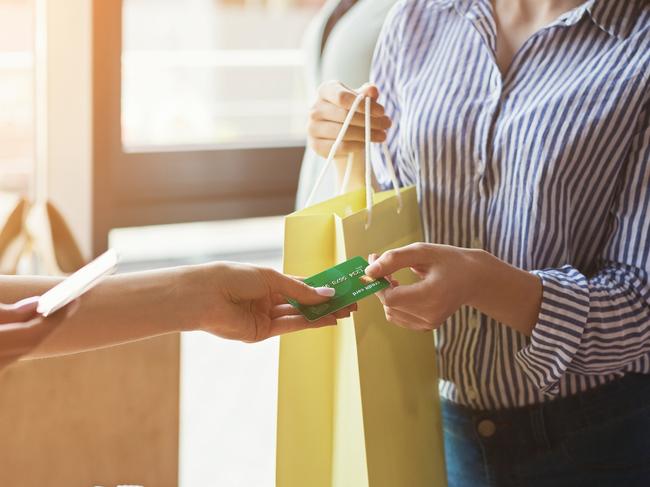 Woman paying with credit card for purchase at clothes showroom. Finance and non-cash transaction concept