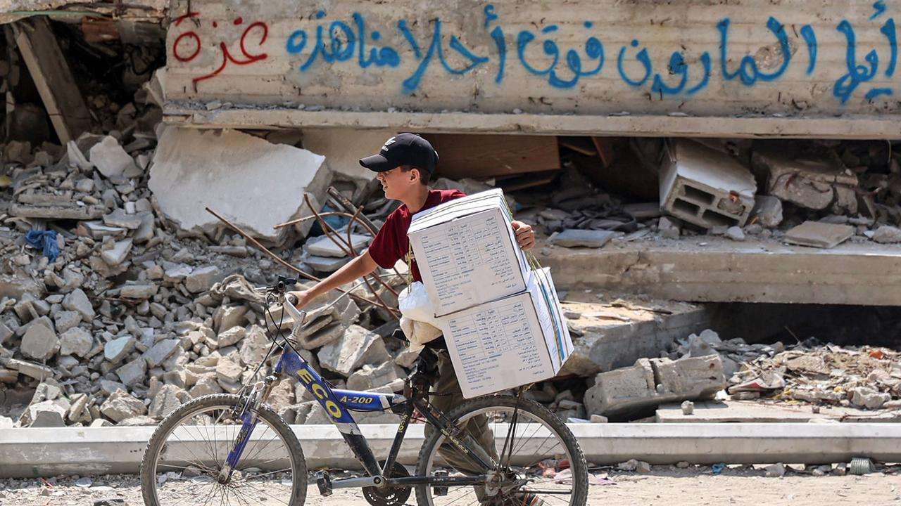 A boy pushes a bicycle loaded with aid boxes provided by the United Nations Relief and Works Agency for Palestine Refugees. Picture: AFP.