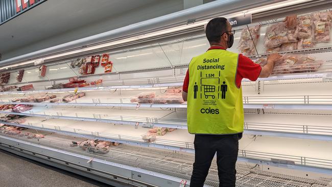 A worker stacks almost empty shelves at Coles New Farm in Brisbane's inner-north. Picture: David Clark