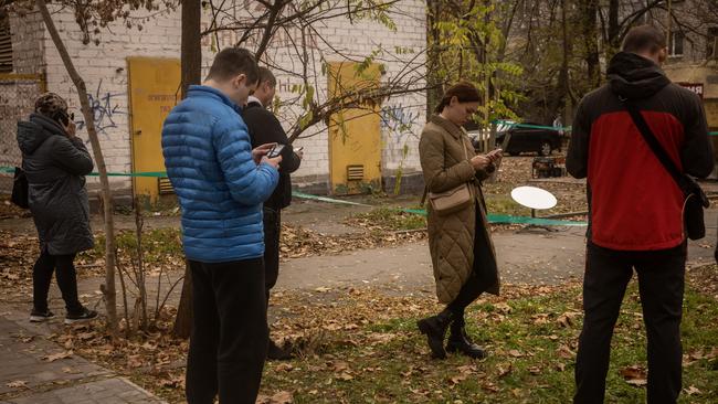 Residents use their phones in an area of the city centre that has temporary phone network and a Starlink device on November 16, 2022 in Kherson, Ukraine. Picture: Chris McGrath/Getty Images