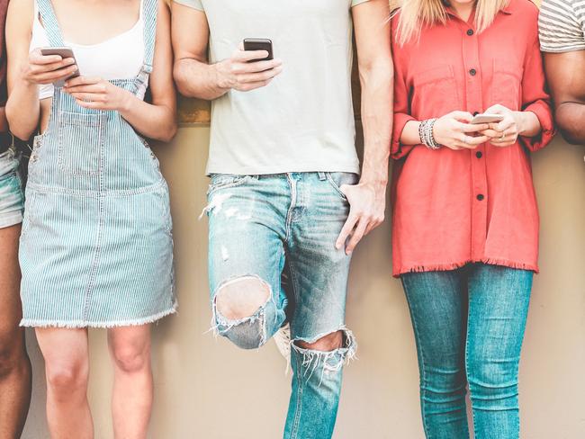 Group of millennial friends watching smart mobile phones - Teenagers addiction to new technology trends - Concept of youth, tech, social and friendship - Focus on smartphones