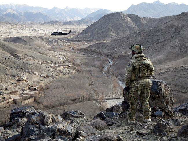 An Australian Army soldier from Special Operations Task Group maintains a watchful eye over Chenartu village in Uruzgan province, Afghanistan, as a US Army Black Hawk helicopter circles above a 'shura' (town meeting) being conducted. *** Local Caption *** Australian Army soldiers from Special Operations Task Group work alongside Afghan National Security Force police officers from Uruzgan’s Provincial Response Company (PRC-U) to conduct operations in support of the Afghan government. Continued effort in Uruzgan and Kandahar over the winter months has led to the removal of prominent insurgents and the recovery of several hidden weapons caches, including stores of improvised explosive device (IED) components that would have otherwise been used to target Afghan civilians and coalition forces. SOTG comprises personnel from the Special Air Service Regiment, 1st and 2nd Commando Regiments, Incident Response Regiment, Special Operations Logistics Squadron and a variety of supporting units from the ADF.