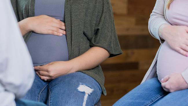 Group of young adult Hispanic and Caucasian pregnant women are meeting for a prenatal support group or childbirth class with midwife or doctor.