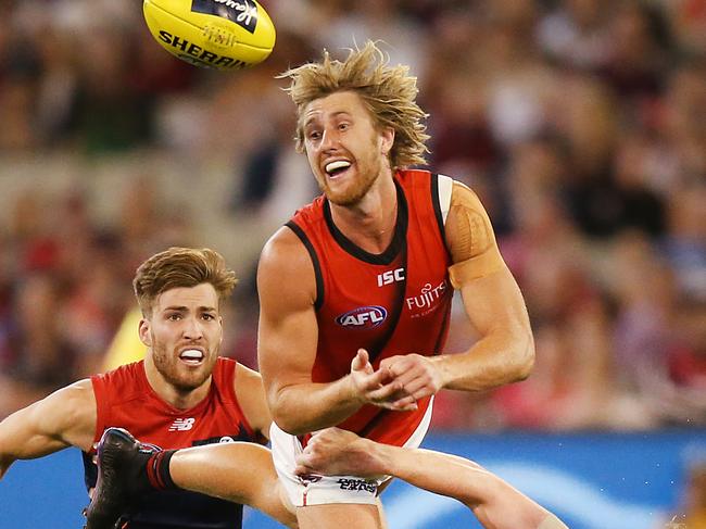 MELBOURNE, AUSTRALIA - APRIL 05: Dyson Heppell of the Bombers handballs to Zach Merrett of the Bombers from Clayton Oliver of the Demons  during the round three AFL match between the Melbourne Demons and the Essendon Bombers at Melbourne Cricket Ground on April 05, 2019 in Melbourne, Australia. (Photo by Michael Dodge/Getty Images)