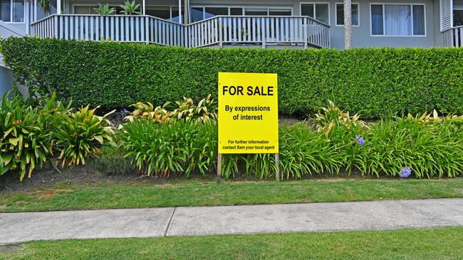 Yellow and black real estate for sale sign in front of a property