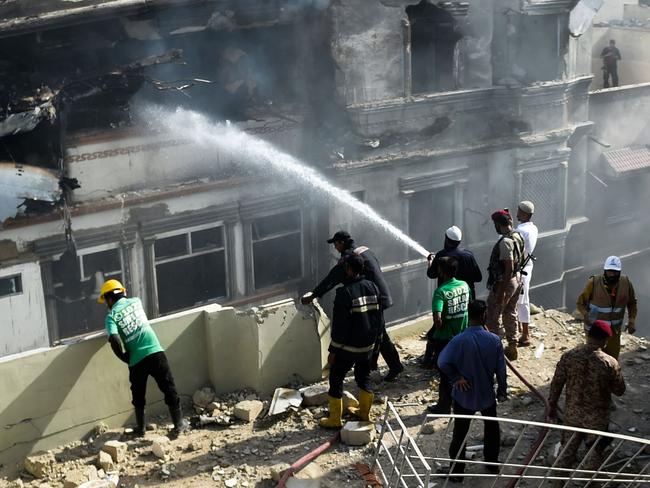 A firefighter sprays water on a burnt building after a Pakistan International Airlines aircraft crashed in a residential area in Karachi on May 22, 2020. - A Pakistani plane with nearly 100 people on board crashed into a residential area in the southern city of Karachi on May 22, killing several people on the ground. (Photo by Rizwan TABASSUM / AFP)