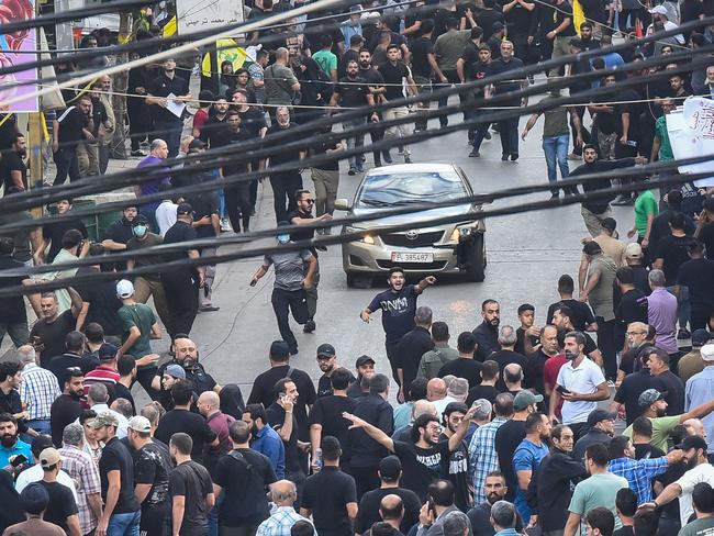 TOPSHOT - People react around a car after a reported explosion occurred during the funeral of those killed when hundreds of paging devices exploded across Lebanon the previous day, in Beirutâs southern suburbs on September 18, 2024. A second wave of device explosions killed three people in Hezbollah strongholds of Lebanon on September 18, raising fears of an all-out war between Israel and the Iran-backed militants. (Photo by Fadel ITANI / AFP)