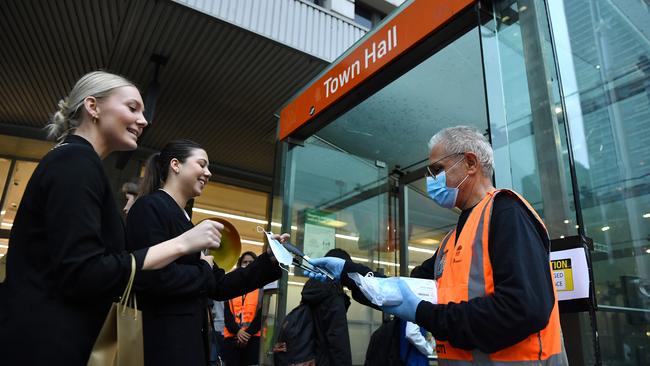 A NSW Transport worker handing out free face masks for commuters at Town Hall. Picture: Joel Carrett