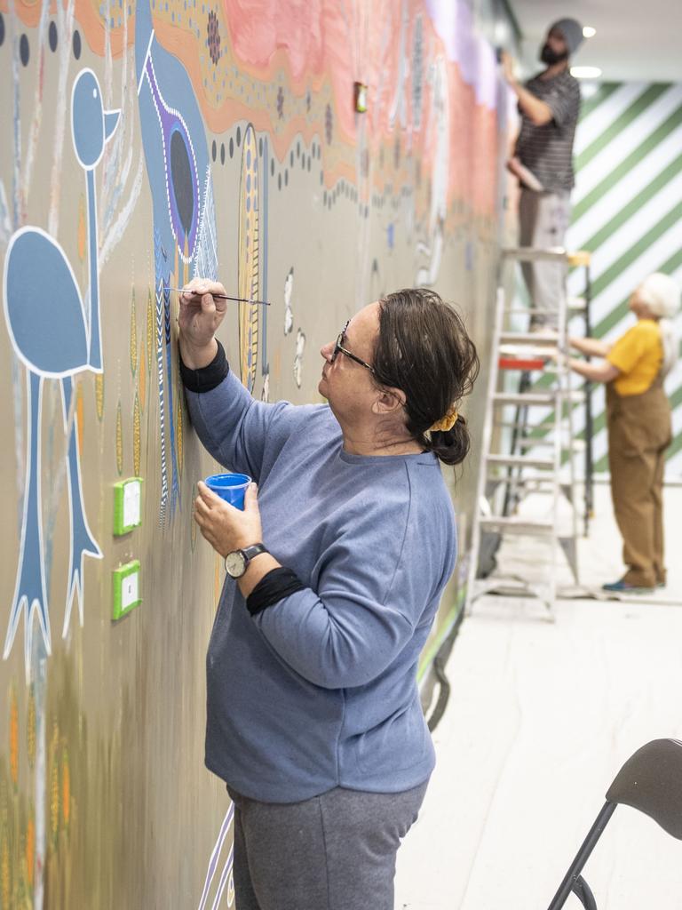 Indigenous artist Cheryl Moggs is painting a mural in Grand Central Shopping Centre, in collaboration with (back from left) artist Aaron (Dhuril) Blades and curator Jennifer Wright (Summers). Thursday, July 7, 2022. Picture: Nev Madsen.