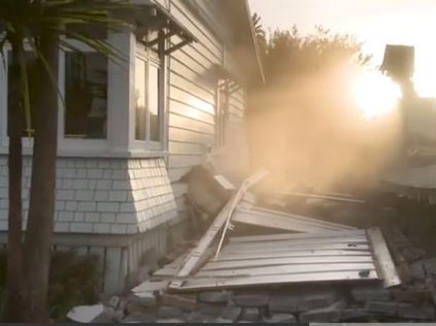 The moment a house in Auckland is damaged during the demolition of a neighbouring property.