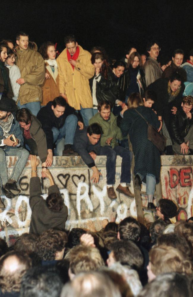 On Saturday November 11, 1989, hundreds of people climbed the wall and demanded it be pulled down. Picture: AP Photo/Lutz Schmidt, File.