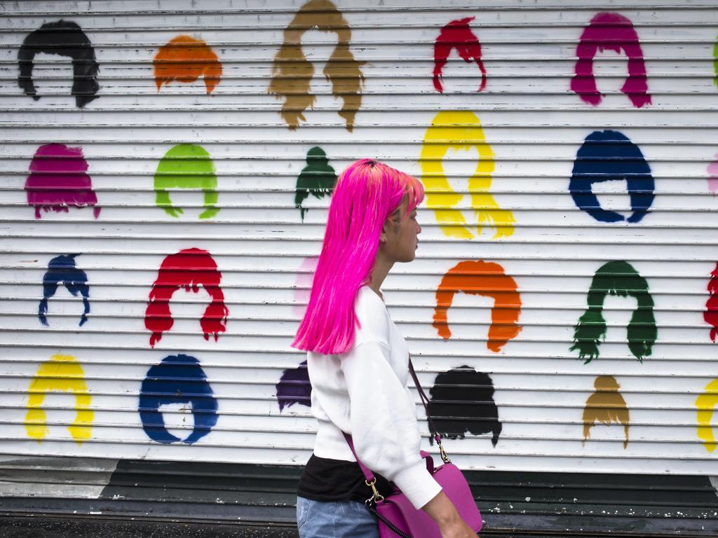 A woman with pink hair walks along Hollywood Boulevard past a colorful storefront shutter Wednesday, July 18, 2018, in Los Angeles. (AP Photo/Jae C. Hong)
