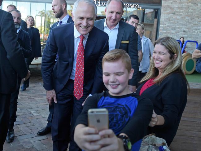 Australian Prime Minister Malcolm Turnbull takes a selfie with a young shopper during a street walk at the North Lakes shopping centre in the federal seat of Petrie in Brisbane. Mr Turnbull has headed back to Queensland where he will again campaign in Brisbane, returning to the coalition’s proposal to cut the small business tax rate and shake up the culture of the construction industry. (AAP Image/Lukas Coch)