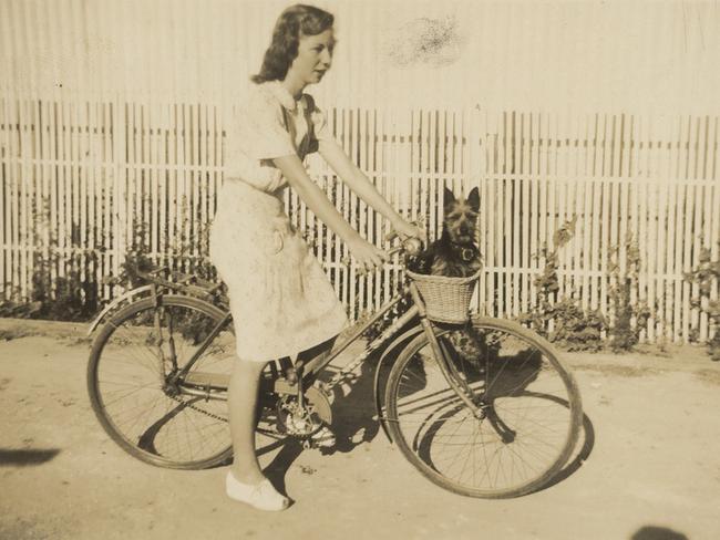 Faye Howell, of Edwardstown, on her bike outside her home with a small terrier in the wicker basket.