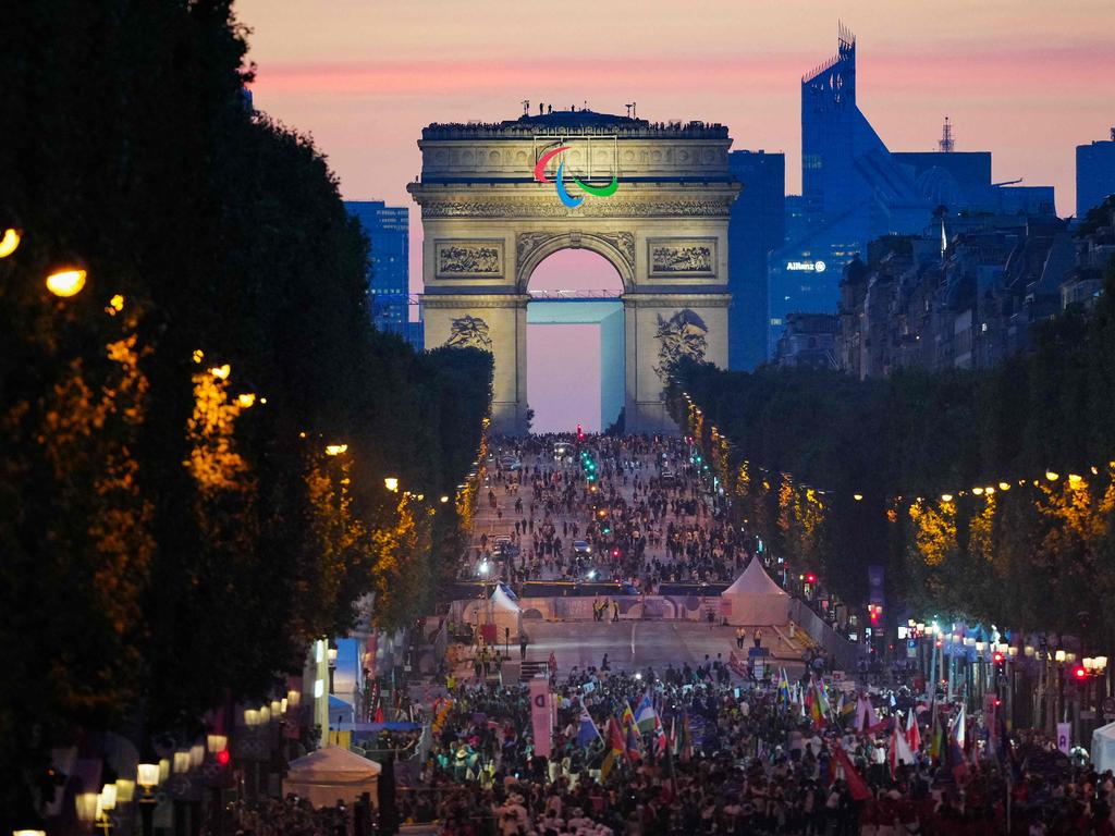 TOPSHOT - Athletes from different delegations parade on the Champs-Elysees avenue with the Arc de Triomphe in the background, during the Paris 2024 Paralympic Games Opening Ceremony in Paris on August 28, 2024. (Photo by Dimitar DILKOFF / AFP)