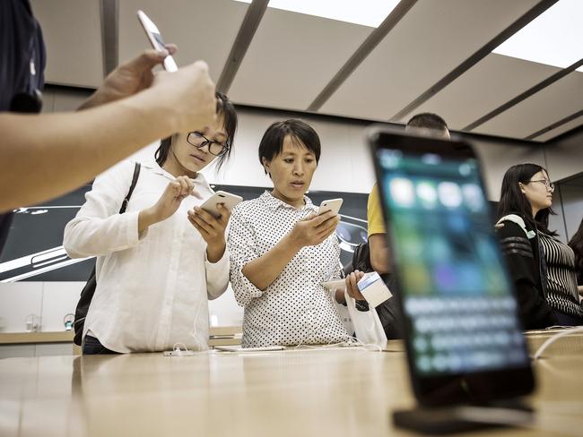 Customers look at the latest iPhone at the Apple Store inside the IAPM shopping mall in Shanghai, China. Picture: Qilai Shen/Getty Images