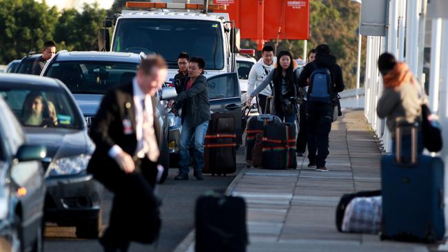 People unload luggage on the ramp to Sydney International Airport due to traffic jams getting to the terminal door. (Pic: News Corp)