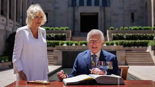 Britain’s King Charles III signs a visitor’s book as Queen Camilla stands next to him at the Australian War Memorial in Canberra on October 21, 2024. Picture: Brook Mitchell / POOL / AFP