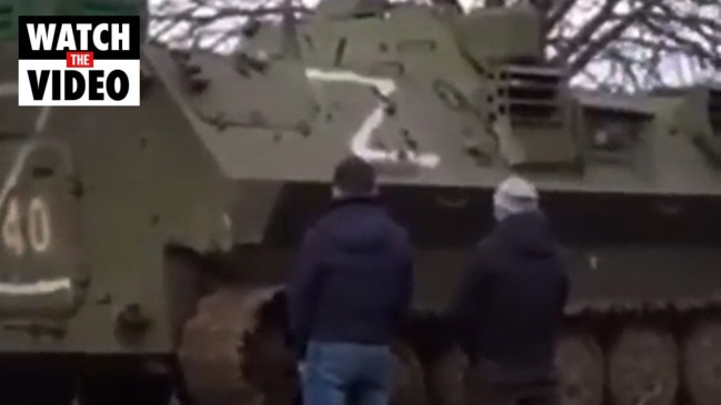 Ukrainian men urinate on tank