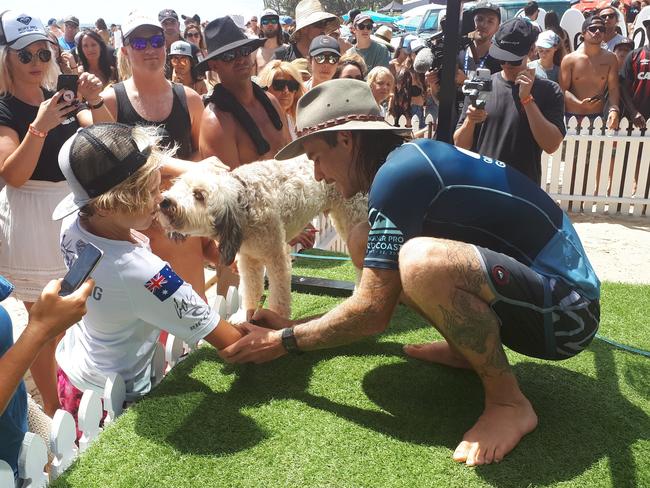 Mikey Wright signs an autograph at the Quiksilver Pro as his dog Bacon gets involved.