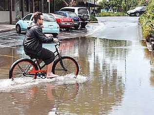 A keen cyclist makes his way through flooding at Byron Bay after the town copped a massive morning shower. Picture: Greg Cromwell