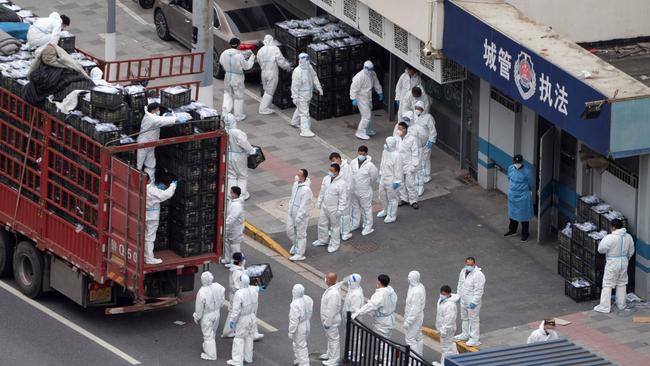 People wearing personal protective equipment transfer daily food supplies and necessities for local residents during lockdown in Shanghai. Picture: AFP