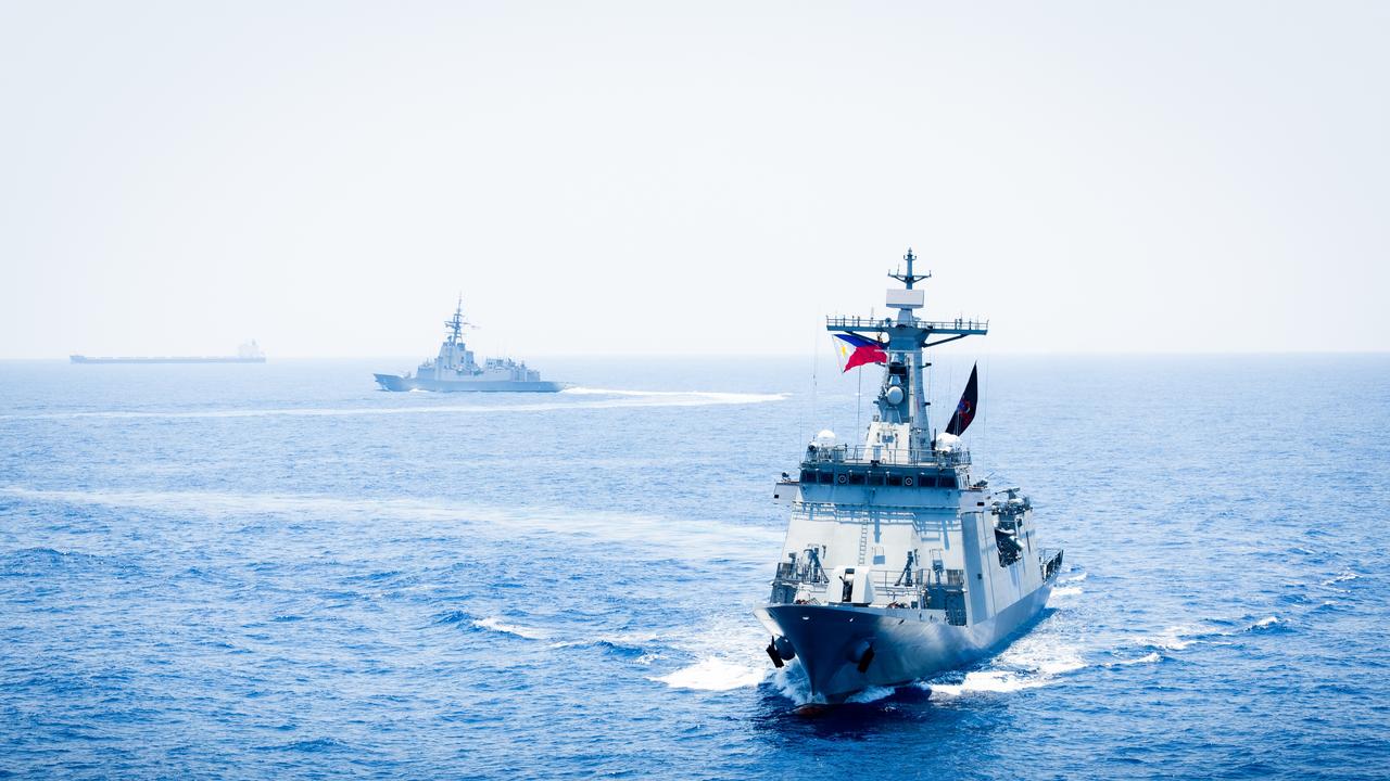 HMAS Sydney (background) is currently on deployment alongside Filipino and US navy vessels in the South China Sea.