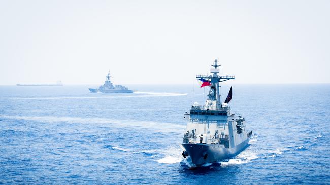 HMAS Sydney (background) is currently on deployment alongside Filipino and US navy vessels in the South China Sea.