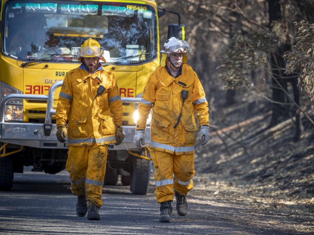 Carl Mills and Peter Orth of the Queensland Fire Brigade help to put out spot fires. Picture: AAP