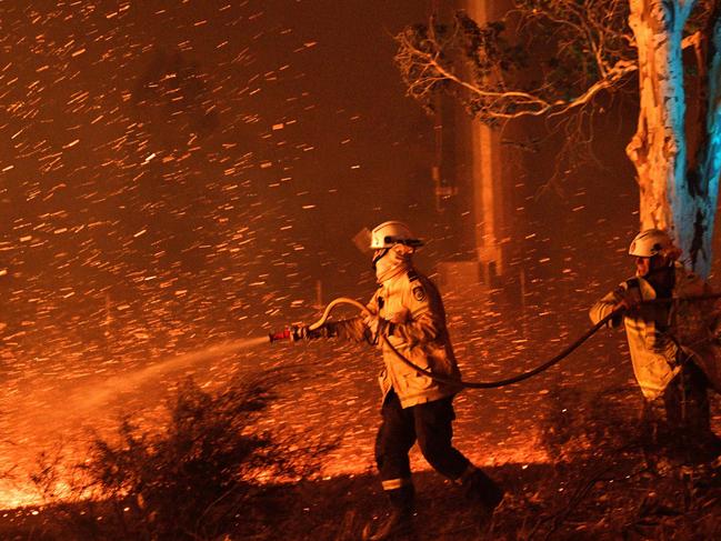 Firefighters hosing down embers to secure nearby houses from bushfires near the town of Nowra in the Australian state of New South Wales. Picture: AFP