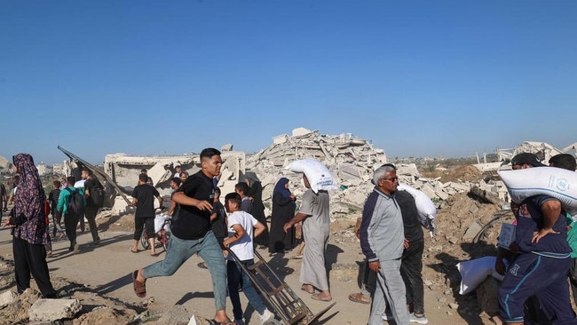 A man rushes to get his share of food aid in Gaza this week. Visas issued to 3000 people from the war zone was ‘simply importing trouble’. Picture: AFP