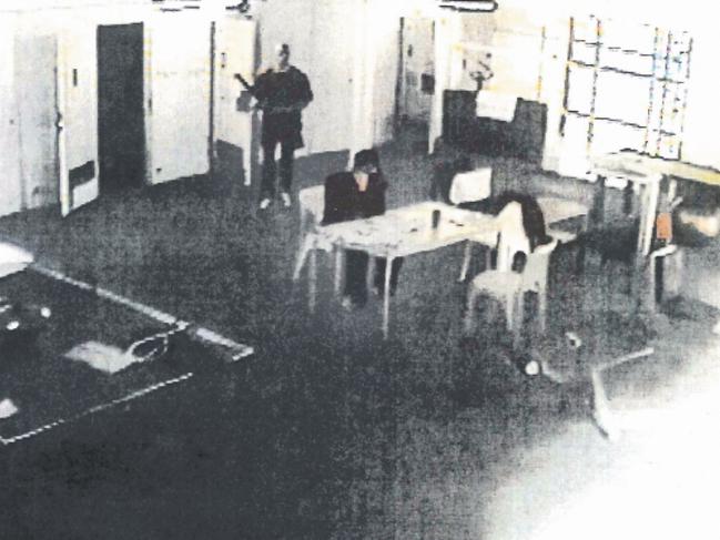 A CCTV still showing Carl Williams seated at a table in the final seconds of his life as his killer, Matthew Johnson, stalks him from behind.