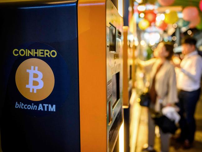 People stand next to bitcoin ATM's outside a cryptocurrency exchange in Hong Kong on November 14, 2024. (Photo by Mladen ANTONOV / AFP)