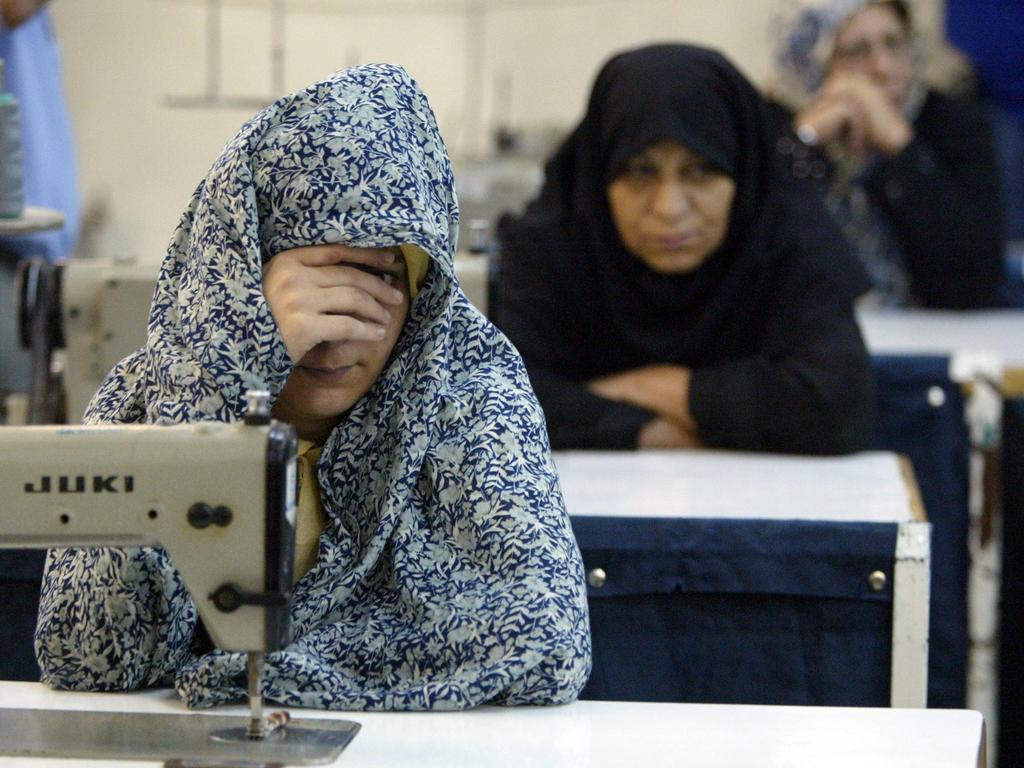 An Iranian woman prisoner covers her face as prisoners work with sewing machines in June 2006. Picture: Mohammad Kheirkhah/UPI Photo