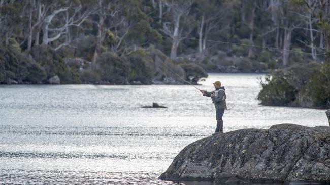 A fly fisherman casts from Halls Island on Lake Malbena, the proposed site of an exclusive luxury camping project. Picture: ROB BLAKERS