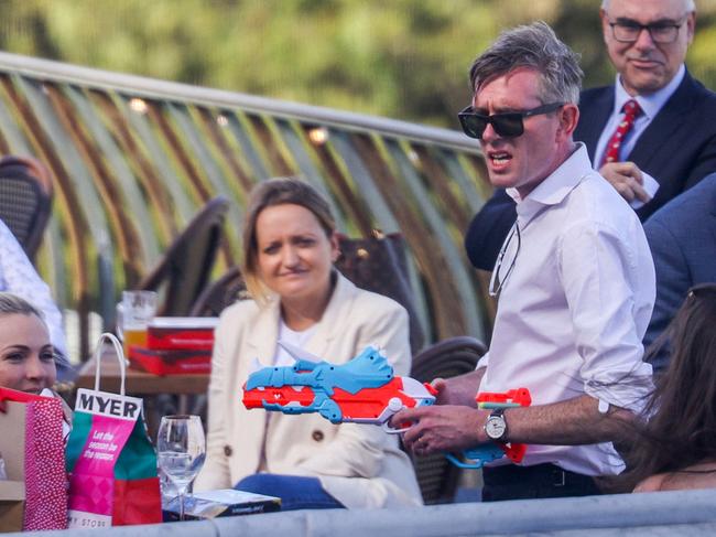 NSW Premier Dominic Perrottet wielding a plastic toy gun he received in a Secret Santa gift exchange.