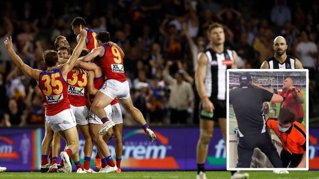 A Collingwood fan is restrained after abusing the umpires.