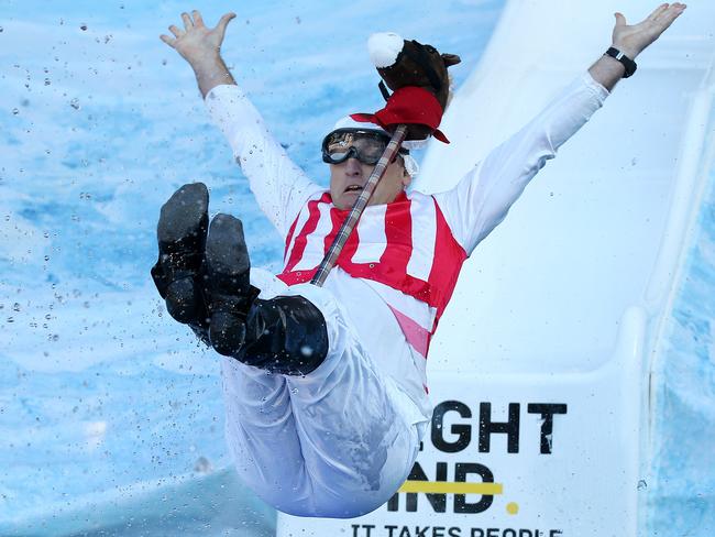 Swans coach John “Horse” Longmire goes down the slide as a jockey. Picture: Michael Klein