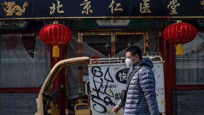 A man wearing a protective facemask walks past a closed restaurant in Beijing. Picture: AFP