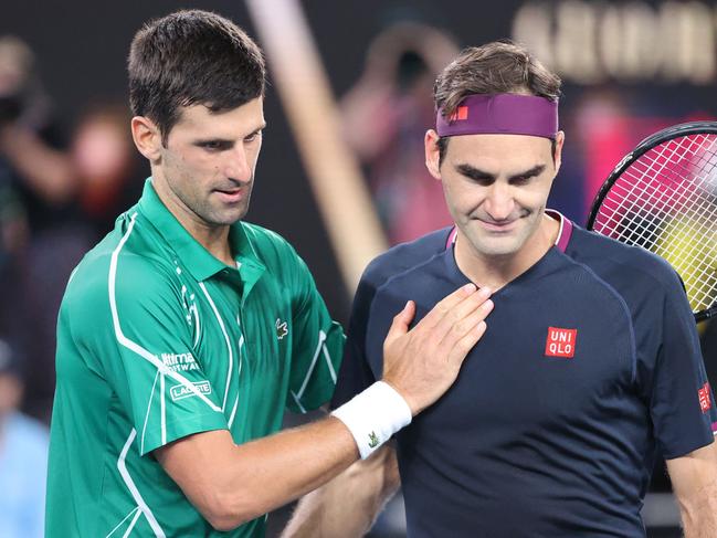 TOPSHOT - Serbia's Novak Djokovic (L) pats Switzerland's Roger Federer after his victory during their men's singles semi-final match on day eleven of the Australian Open tennis tournament in Melbourne on January 30, 2020. (Photo by DAVID GRAY / AFP) / IMAGE RESTRICTED TO EDITORIAL USE - STRICTLY NO COMMERCIAL USE