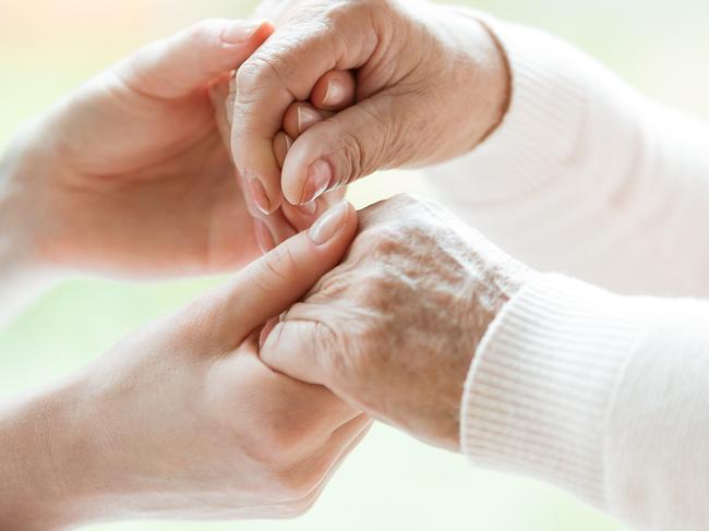 Photo with close-up of caregiver and patient holding hands