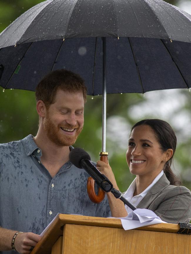 Meghan holds an umbrella while Prince Harry did his speech in the rain. Picture: Ian Vogler/AP