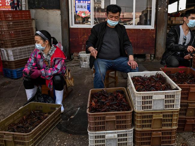 TOPSHOT - This photo taken on April 15, 2020 shows vendors wearing face masks as they offer prawns for sale at the Wuhan Baishazhou Market in Wuhan in China's central Hubei province. - China's 