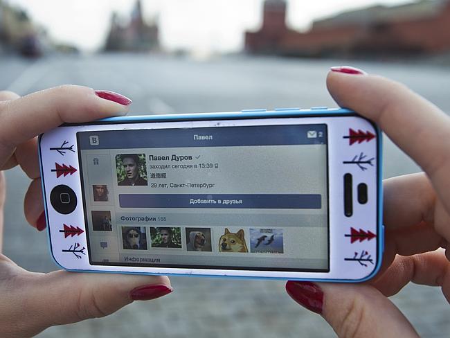 A user of Russia’s leading social network internet site VKontakte, poses holding an iPhone showing the account page of Pavel Durov.