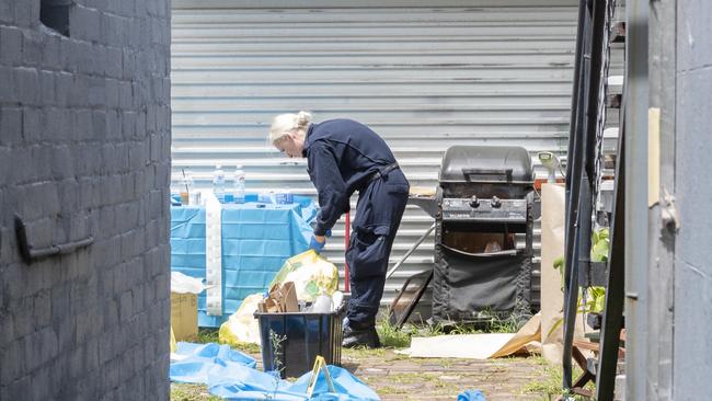 A police officer searches items at the boarding house. Picture: Monique Harmer