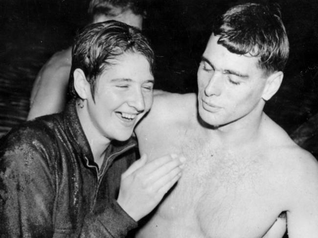 John Devitt helps Dawn Fraser out of the water after she was dunked, tracksuit, medal and all, after winning the women's 110 yards event in world record time at the Commonwealth Games in Cardiff. Picture: AP Photo