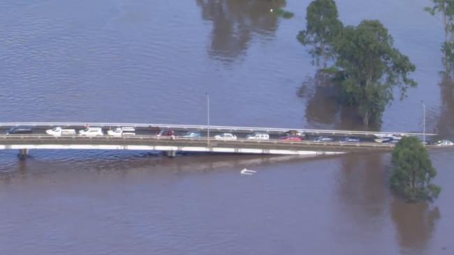 Aerial footage shows horses and more than a dozen cars stranded on Woodburn Bridge, about 34km south of flood-devastated Lismore. Images: Seven