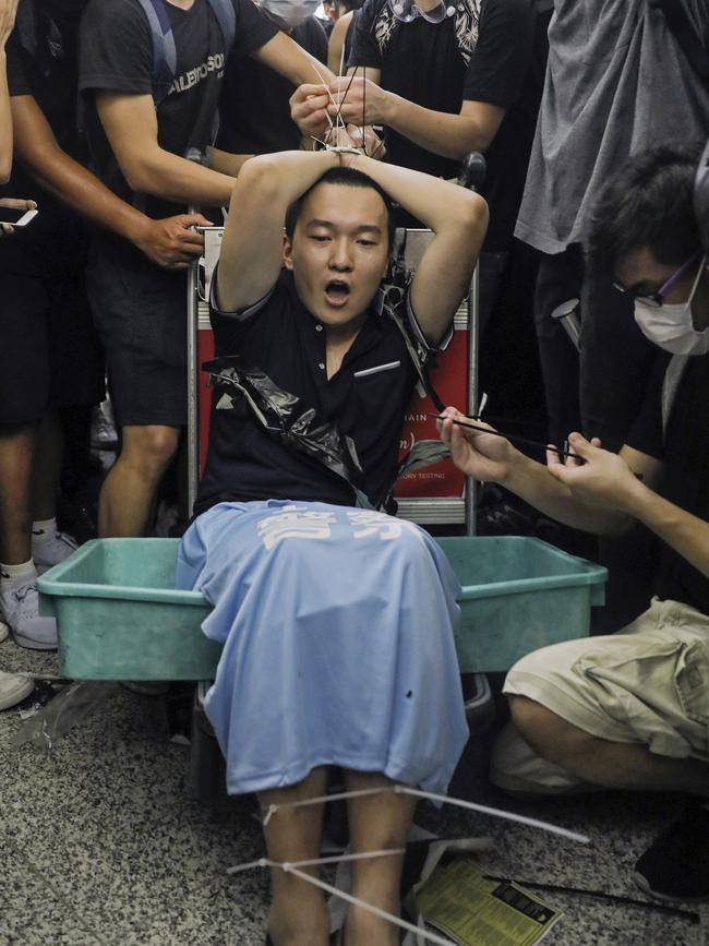 Protesters restrain a man on a luggage trolley, who protesters claimed was a Chinese undercover agent. Picture: AP.