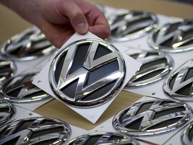 Reputation in tatters ... a Volkswagen employee picks up a logo to be fitted. Picture: AFP