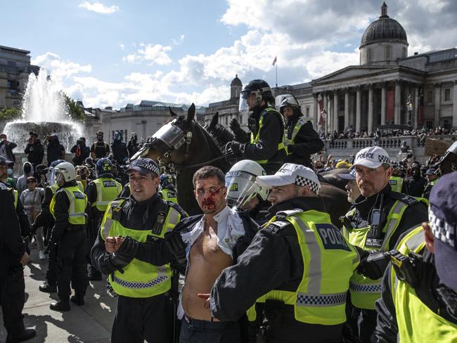 Police lead an injured man away after clashes between protesters in Trafalgar Square. Picture: Getty